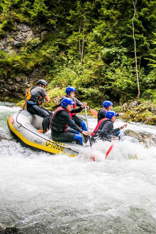 A group grows together during water sports activities in Hinterstoder along the current of the river.