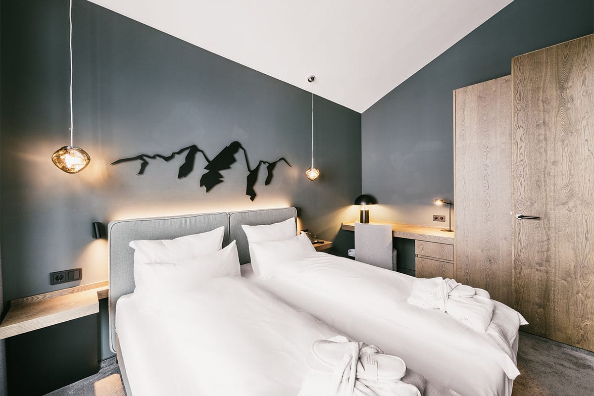 One of the two bedrooms of the Superior Family Suite at the Triforêt alpin.resort in Hinterstoder, with a comfy double bed.