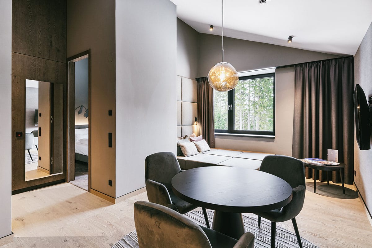 Heller Wohnbereich mit TV in der Suite „Kleiner Priel” im TRIFORÊT alpin.resort in Hinterstoder.