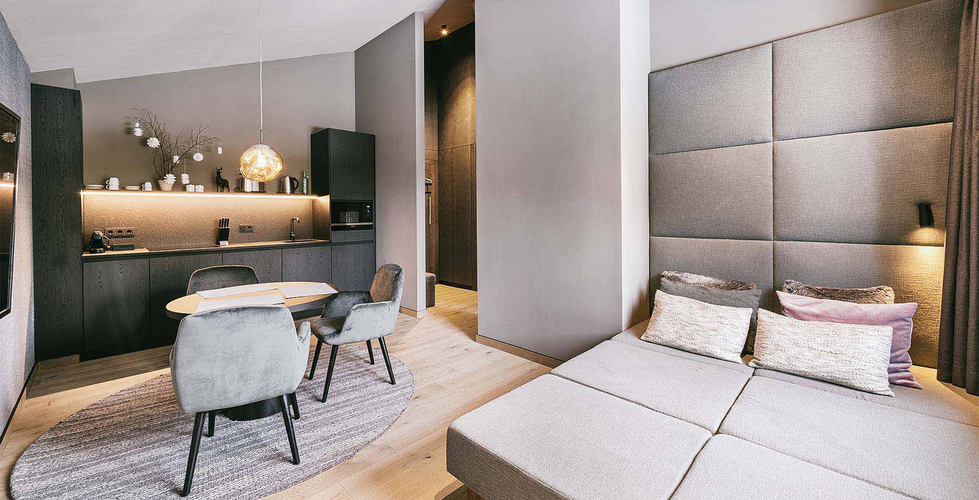 Stylish kitchen and living area with seating in the 1 Bedroom Suite at the TRIFORÊT alpin.resort in Hinterstoder.