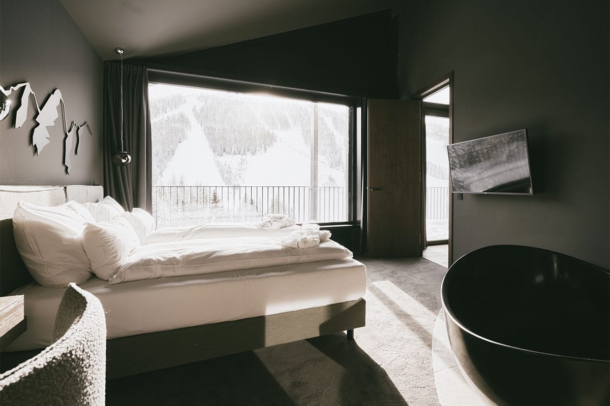 Freestanding bathtub in the Penthouse Suite at the TRIFORÊT alpin.resort with view of the Hinterstoderer landscape.