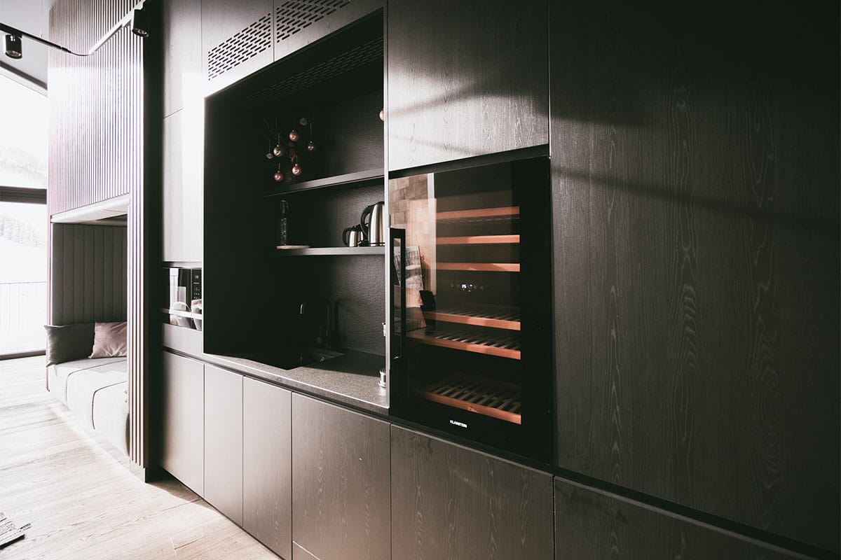 Kitchenette with wine cabinet in the Deluxe Penthouse Suite “Großer Priel” at the TRIFORÊT alpin.resort in Hinterstoder.