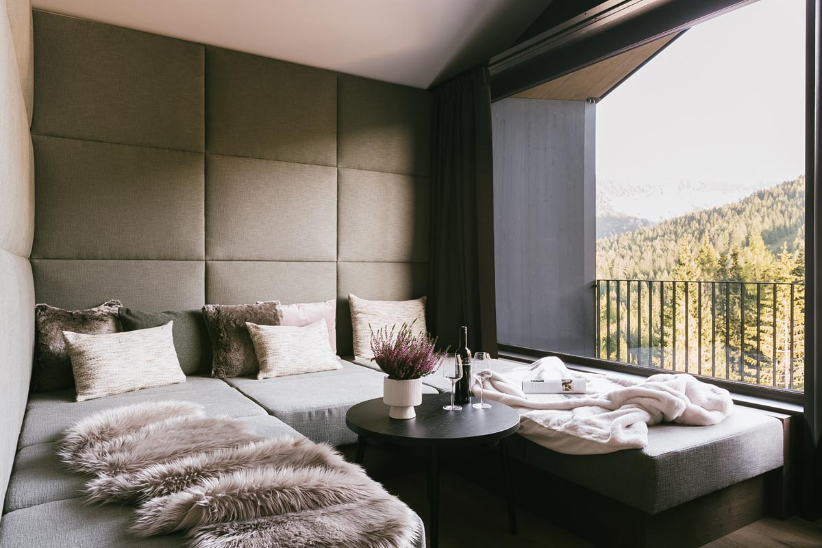 Cosy sofa with a view of the Hinterstoder mountains in the 2 Bedroom Deluxe Suite at the TRIFORÊT alpin.resort.
