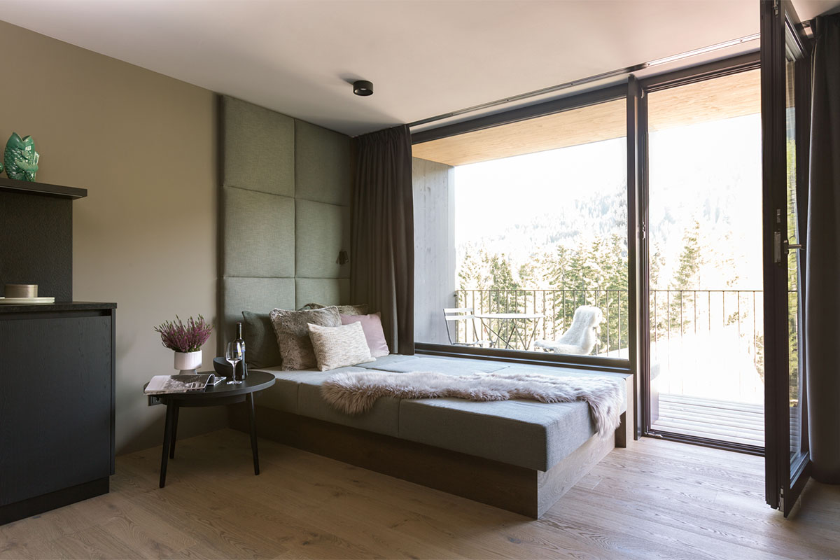 Kitchen and living area of the Family Suite at the TRIFORÊT alpin.resort with a view of the mountain landscape in Hinterstoder.