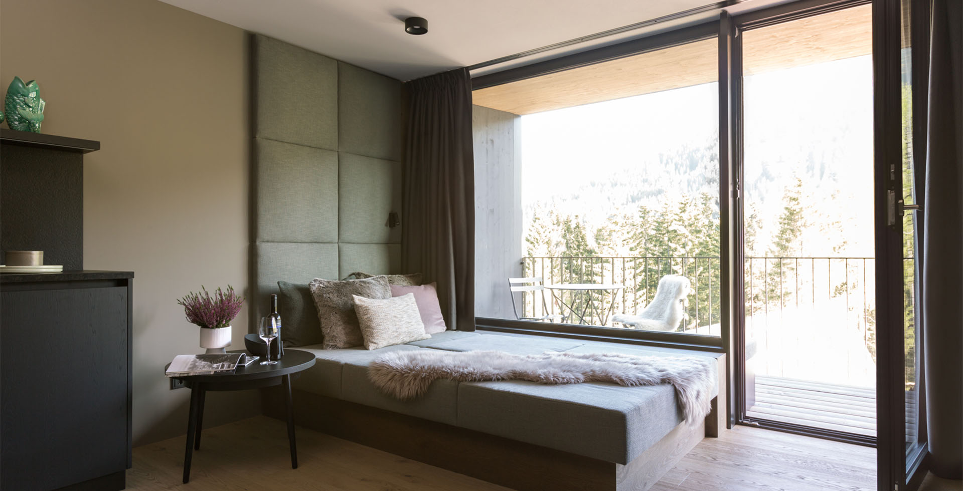 Spacious Family Suite at the TRIFORÊT alpin.resort with dining table, kitchenette, sofa and balcony view of the Alps.