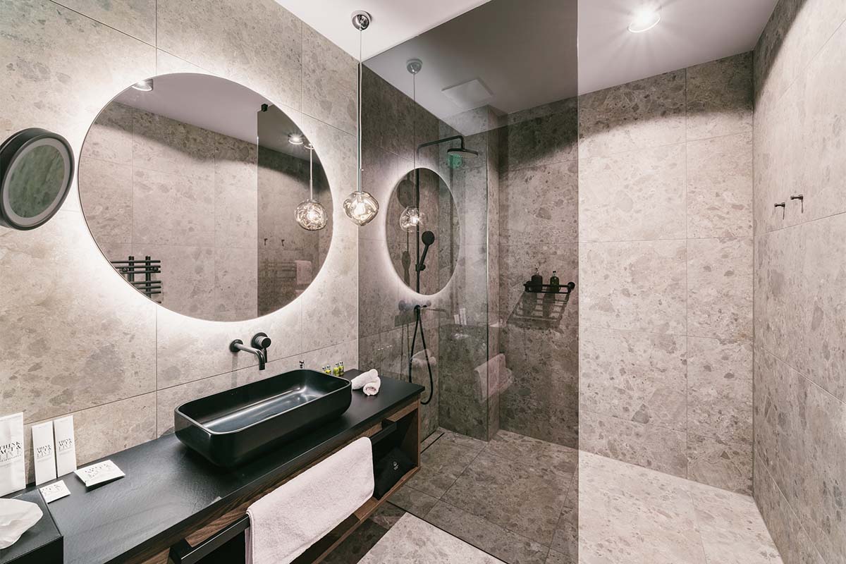 Stylish bathroom with spacious walk-in shower in the Superior Family Suite “Schrocken” at the TRIFORÊT alpin.resort.