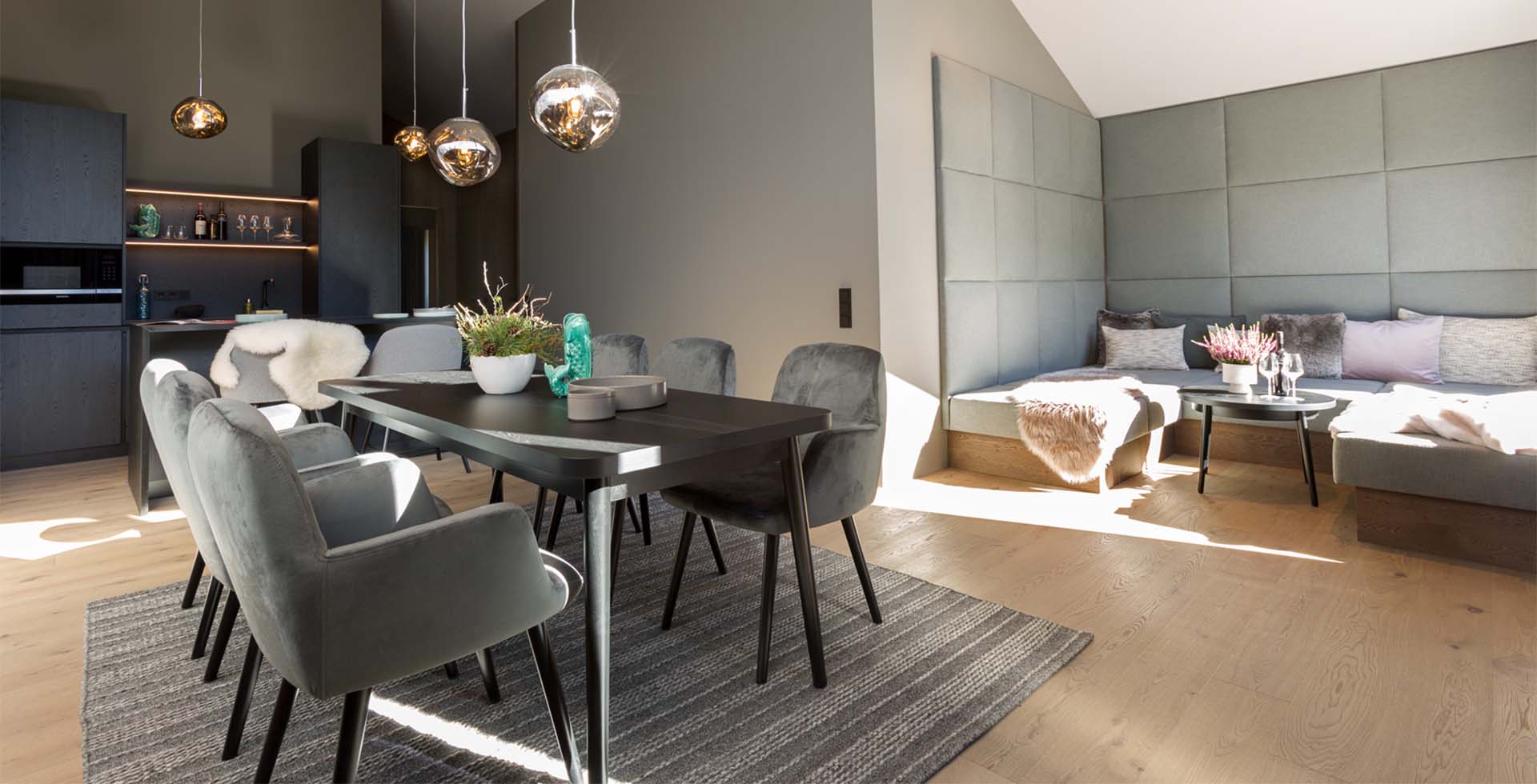 Dining table for six and large sofa in front of the window front and balcony at the TRIFORÊT alpin.resort in Hinterstoder.
