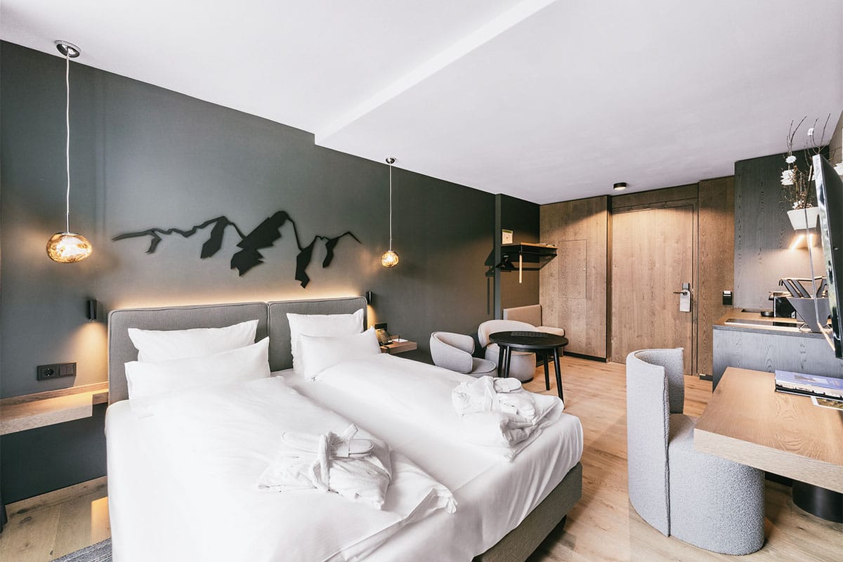 Bright sleeping area with double bed and desk in the studio apartment at the TRIFORÊT alpin.resort in Hinterstoder.