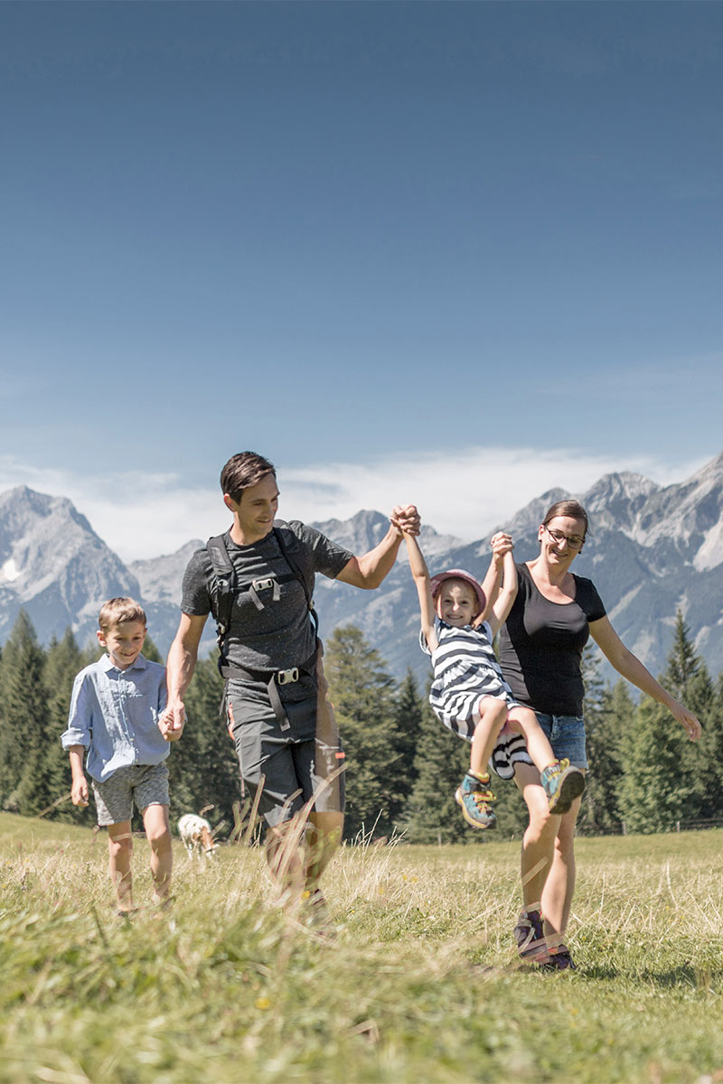 Glückliche Familie auf einer sommerlichen Wanderung durch die Berge im Sommerurlaub im TRIFORÊT alpin.resort.