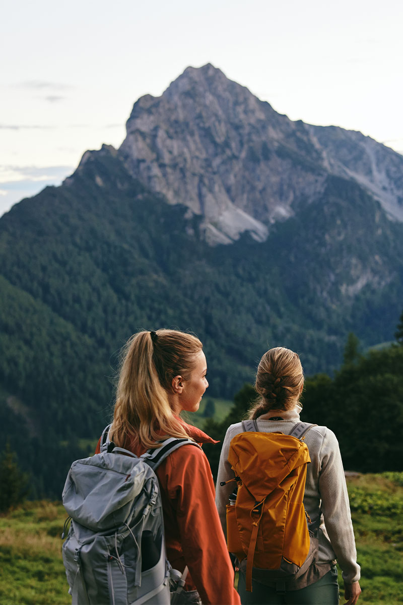 Zwei junge Frauen beim Wandern in Hinterstoder mit Blick auf die Berge im Sommerurlaub im TRIFORÊT alpin.resort.