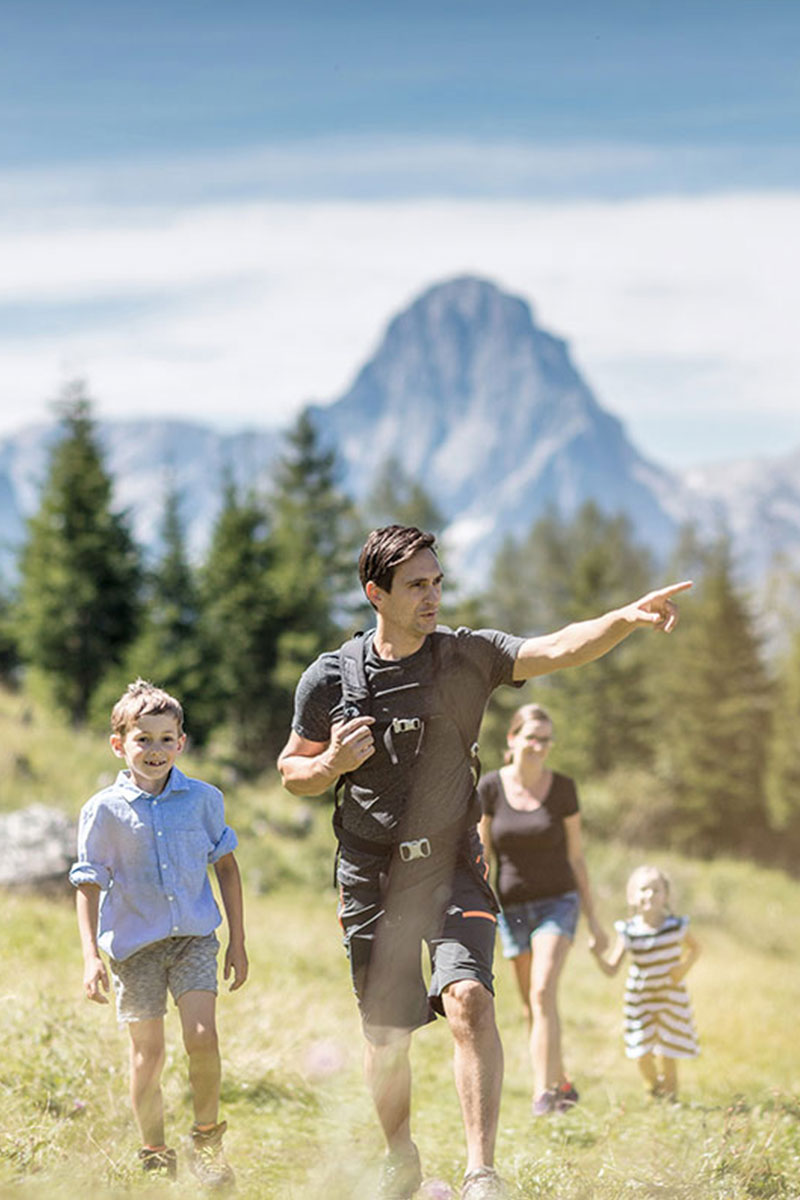 Familie wandert auf einem sonnigen Bergpfad im Sommerurlaub im TRIFORÊT alpin.resort in Hinterstoder.