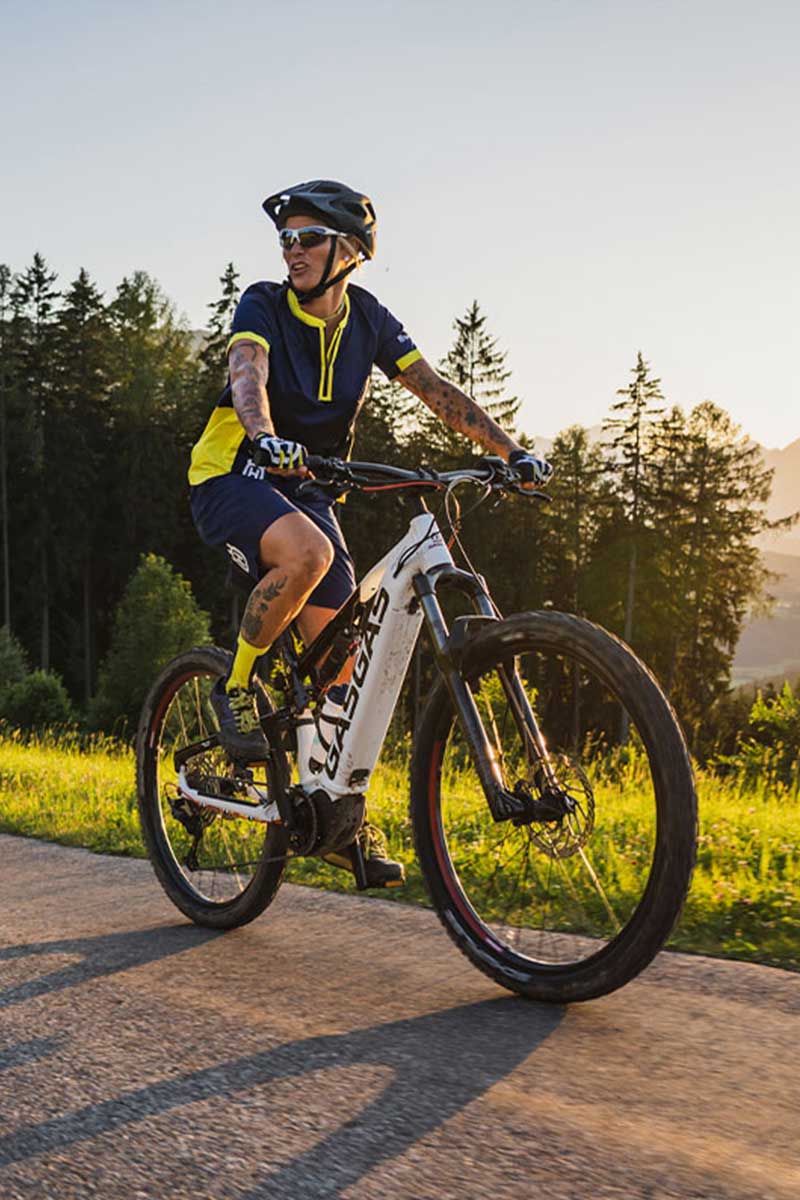 Mountainbiker fährt auf sonniger Allee durch die alpine Natur im Sommerurlaub im TRIFORÊT alpin.resort in Hinterstoder.
