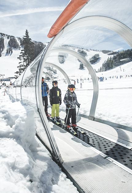 Mit dem gläsernen Skilift genießt eine Familie die Auffahrt auf den Berg.