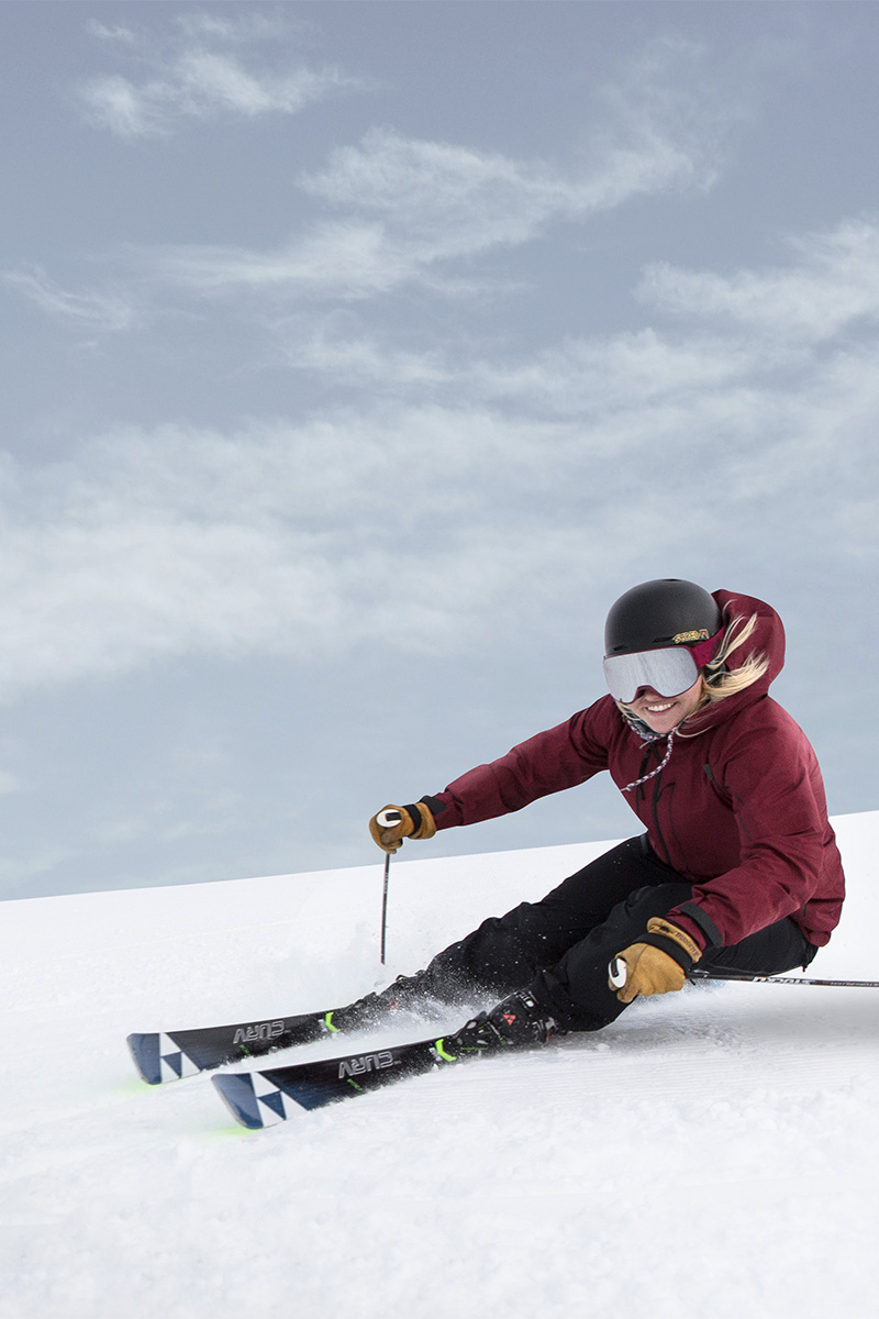 Eine Frau fährt mit den Skiern eine Abfahrt im Schnee hinunter und hat eine Menge Spaß.