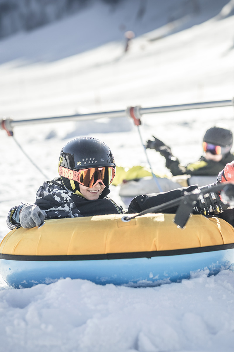 Kinder in einem Gummiboot werden über die Schneelandschaft gezogen und haben jede Menge Spaß.