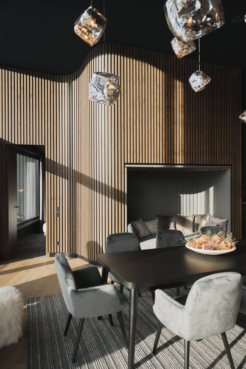 Ein Platz für Genussmomente im Skiurlaub in Hinterstoder. Heller Essbereich mit Designerstühlen, Holzverkleidung und gemütlicher Sitzecke im Chalet im TRIFORÊT alpin.resort.