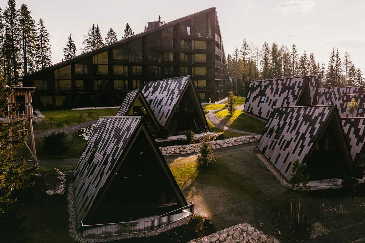 Außenansicht des TRIFORÊT alpin.resort mit Hauptgebäude und Chalets am Waldrand - der perfekte Arbeitsplatz in den Bergen.