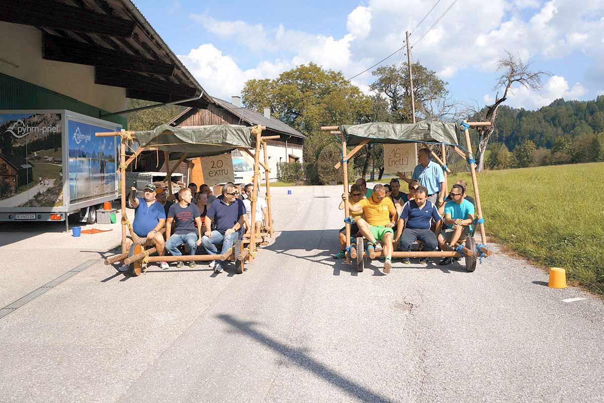 Group of people racing with self-built Stone Age cars at the team-building event at TRIFORÊT alpin.resort.