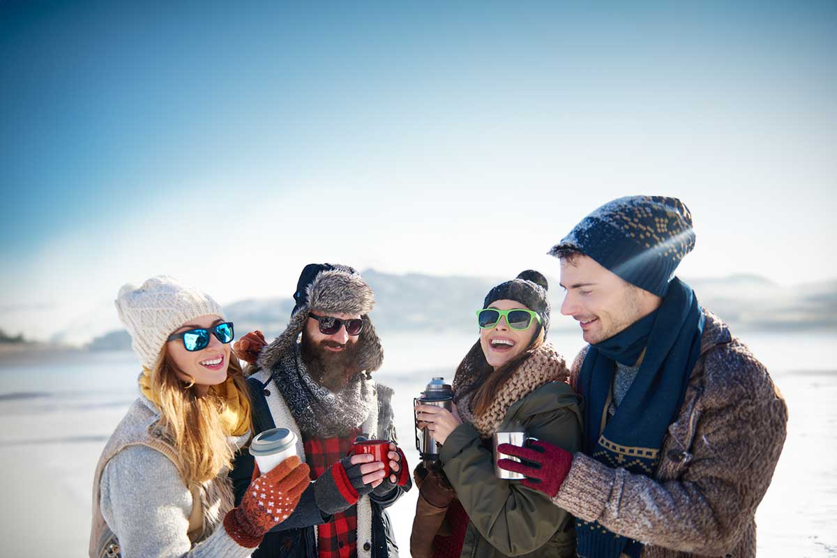 Group of people on a TRIFORÊT alpin.resorts winter tour, wrapped up warm with thermal mugs in hand.