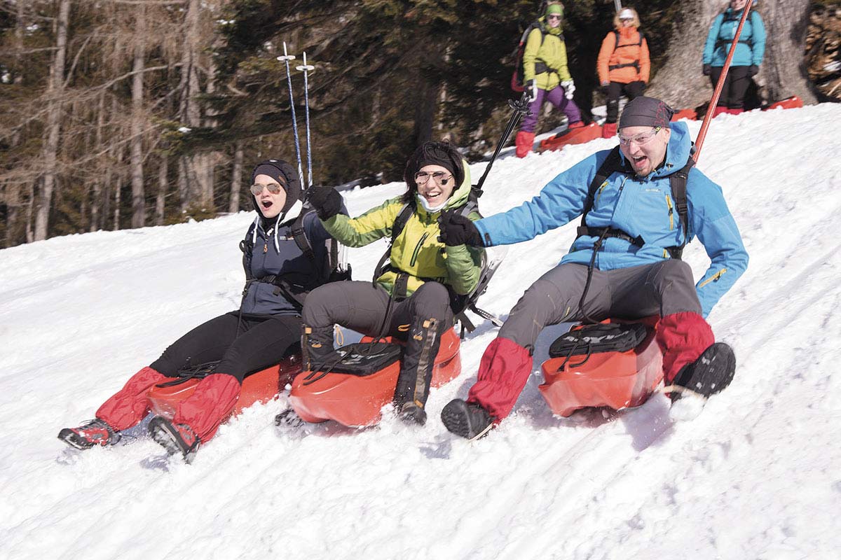 Participants in an incentive program at the TRIFORÊT alpin.resort in Hinterstoder hurtle down a slope on red sledges.